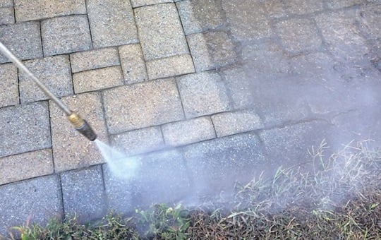 rotating power washer nozzle cleans the paver joints of a patio